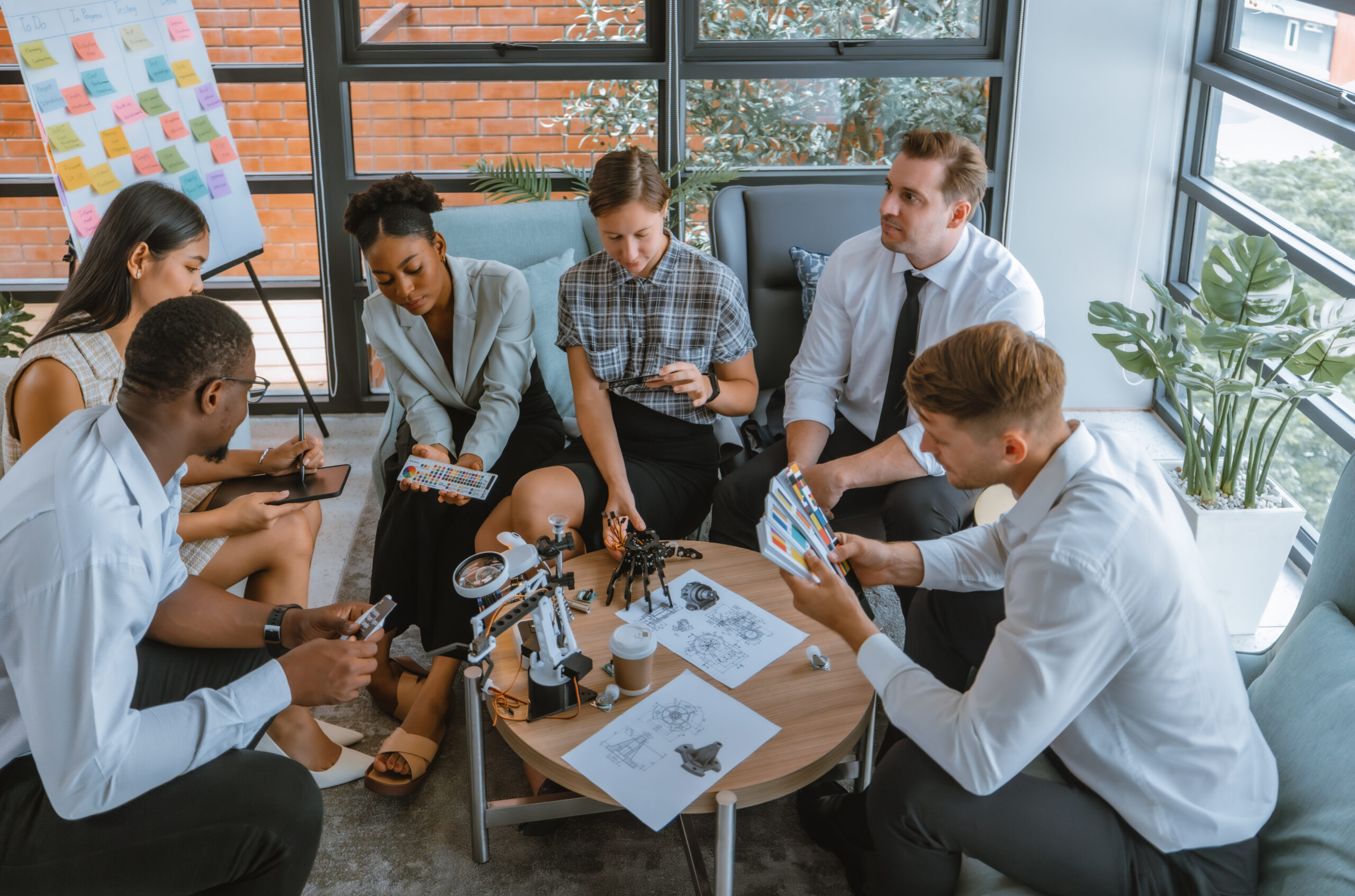 A diverse, agile, multicultural startup team collaborates on an innovative project to develop a robot arm prototype and other AI electronics components for efficient sensory processing automation.